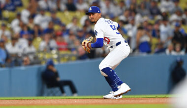 Mookie Betts, wearing a white Dodgers jersey with blue Betts written across the back and a blue cap with the Dodgers logo, prepares to make a throw to first base.
