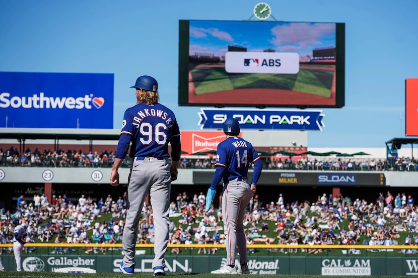 Texas Rangers first base coach Travis Jankowski (96) and infielder Tyler Wade (14) look up...