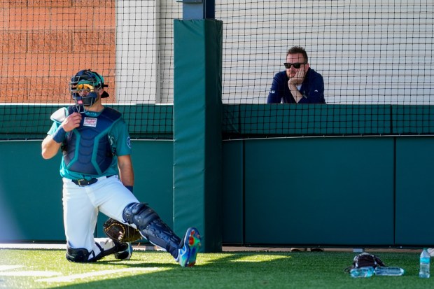 Seattle Mariners general manager Justin Hollander, right, watches as catcher Cal Raleigh works in the bullpen during spring training baseball practice at the team's training facility Tuesday, Feb. 18, 2025, in Peoria, Ariz. (AP Photo/Lindsey Wasson)