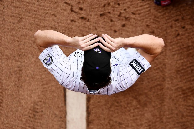 Colorado Rockies starting pitcher Chase Dollander puts on his cap in the bullpen prior to a baseball game against the Arizona Diamondbacks, Saturday, Aug. 16, 2025, in Denver. (AP Photo/Geneva Heffernan)