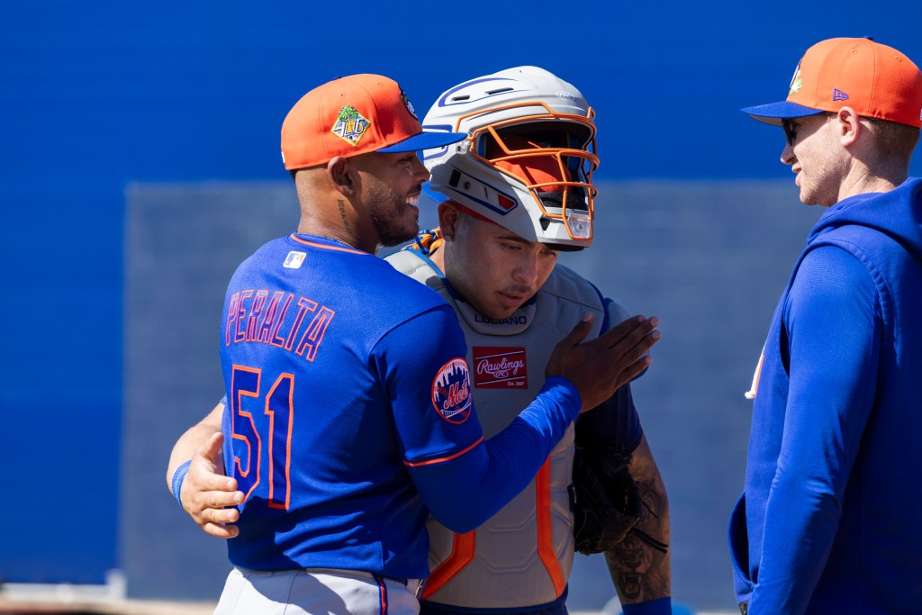 New York Mets pitcher Freddy Peralta, catcher Francisco Alvarez, and pitching coach Justin Willard confer during Spring Training.
