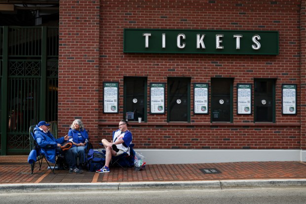 Al Yellon, from left, Miriam Romain and Christopher Sorley wait to get into the bleacher seats outside of Wrigley Field before the Chicago Cubs host the Washington Nationals on opening day, March 26, 2026. (Eileen T. Meslar/Chicago Tribune)
