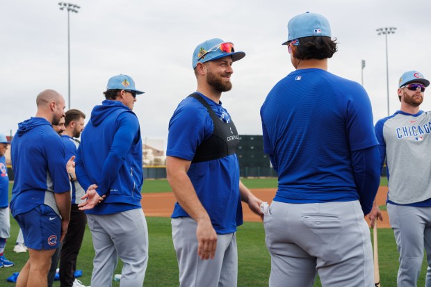 Michael Busch, left, smiles at Miguel Amaya before warming up during Cubs spring training at Sloan Park on Feb. 16, 2026, in Mesa, Ariz. (Armando L. Sanchez/Chicago Tribune)