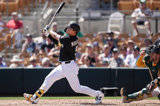 Chicago White Sox's Munetaka Murakami hits a fly ball out to center field as Athletics catcher Austin Wynns looks on during the third inning of a spring training baseball game, Tuesday, March 17, 2026, in Glendale, Ariz. (AP Photo/Ross D. Franklin)