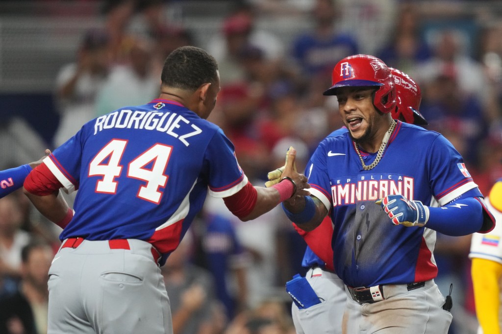 Ketel Marte, wearing a red helmet and blue jersey, celebrates with teammate Julio Rodriguez after hitting a home run.