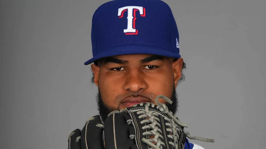 Texas Rangers starting pitcher Jose Corniell holds a baseball glove in front of his face.