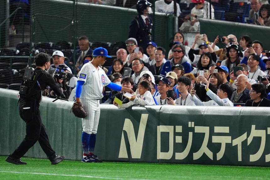 Chicago Cubs pitcher Shota Imanaga presents a ball to a young fan in Tokyo in March 2025.