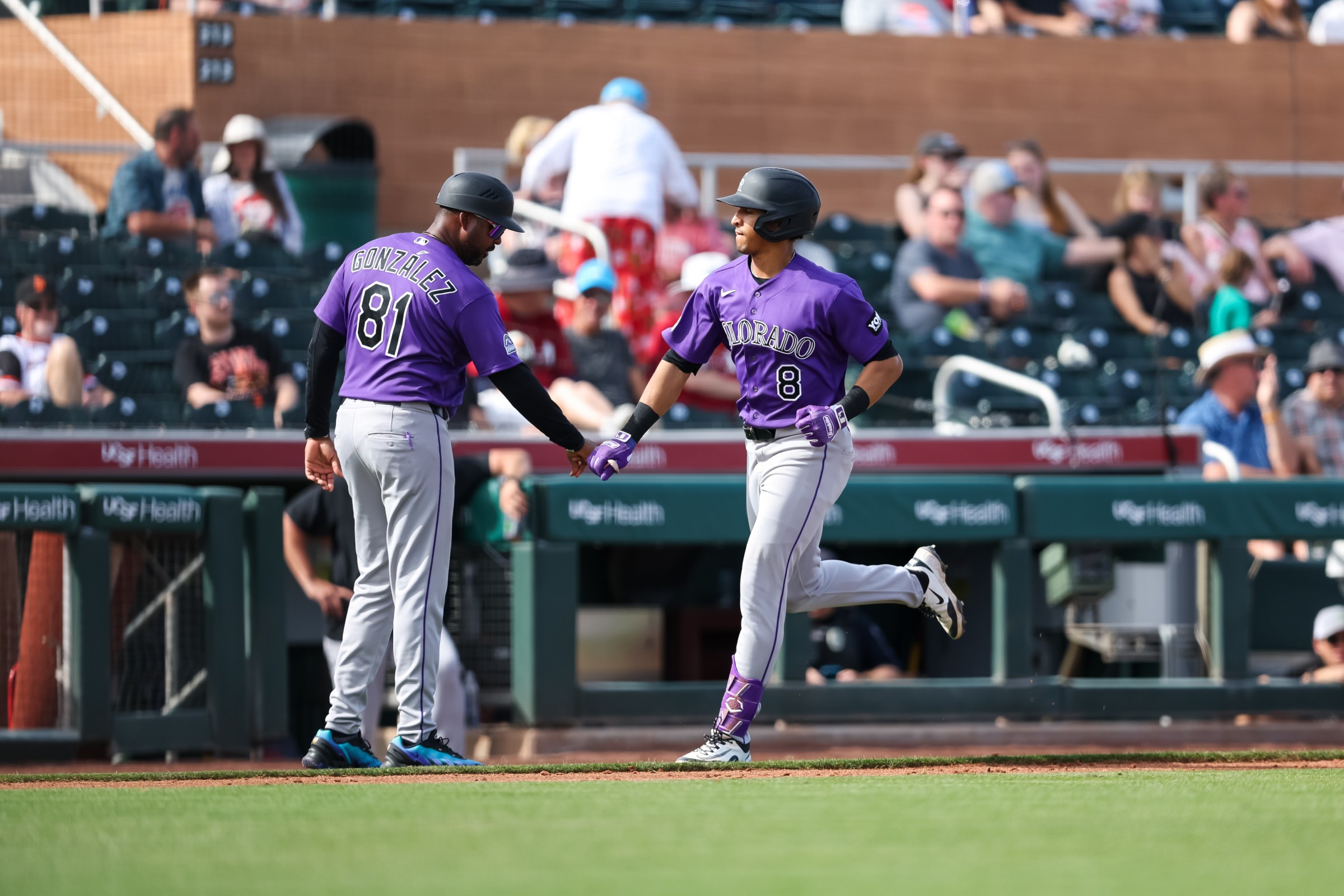 SCOTTSDALE, ARIZONA - FEBRUARY 26: Ryan Ritter #8 of the Colorado Rockies greets third base coach Andy González #81 after hitting a home run during the sixth inning of the spring training game against the San Francisco Giants at Scottsdale Stadium on February 26, 2026 in Scottsdale, Arizona. (Photo by Mike Christy/Getty Images)