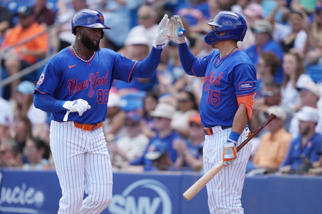New York Mets players Luis Robert Jr. (88) and Tyrone Taylor (15) give each other a high-five.