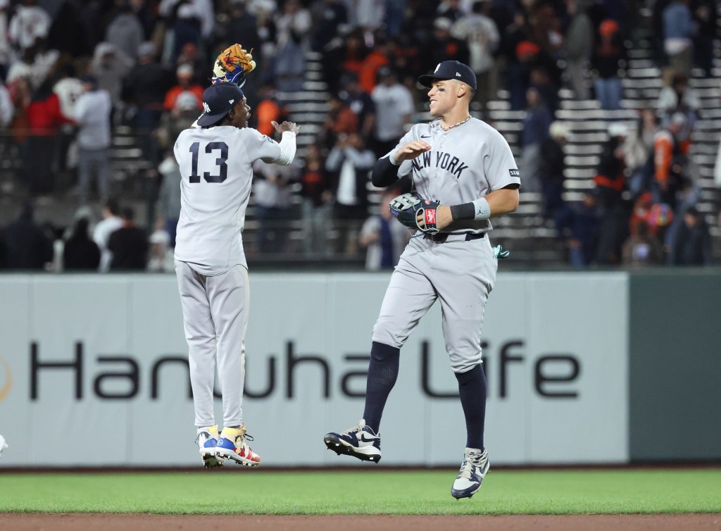 New York Yankees players Aaron Judge (99) and Jazz Chisholm Jr. (13) jumping to celebrate.