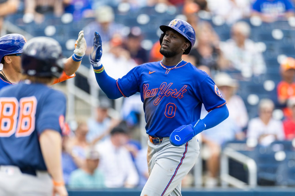 New York Mets player Ronny Mauricio high-fives another player after scoring in a spring training game.