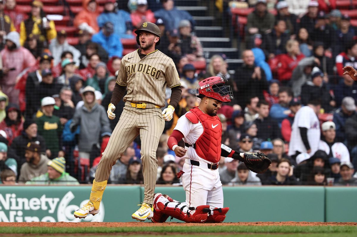 During a baseball game, a player in a beige uniform is seen leaping into the air, possibly in a celebratory gesture, while another player in a red uniform is positioned behind him. The scene takes place on a baseball field, with a crowd of spectators in the stands, creating a vibrant and dynamic atmosphere.