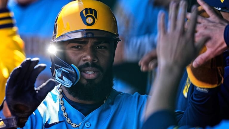 Milwaukee Brewers' Luis Rengifo celebrates in the dugout after scoring...