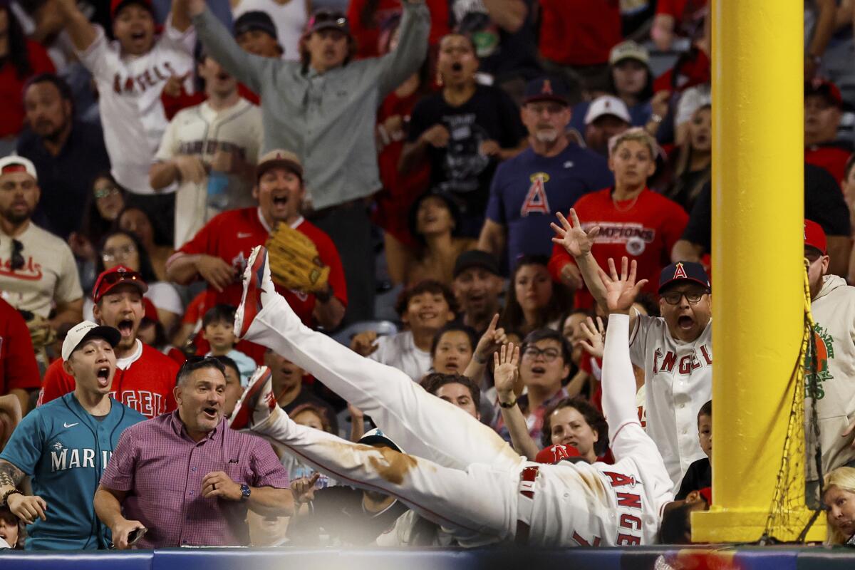 Jo Adell falls into the seats at Angel Stadium after robbing Seattle's J.P. Crawford of a home run