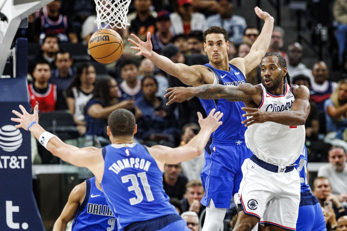 Clippers star Kawhi Leonard, right, passes the ball in front of Dallas Mavericks forward Dwight Powell.