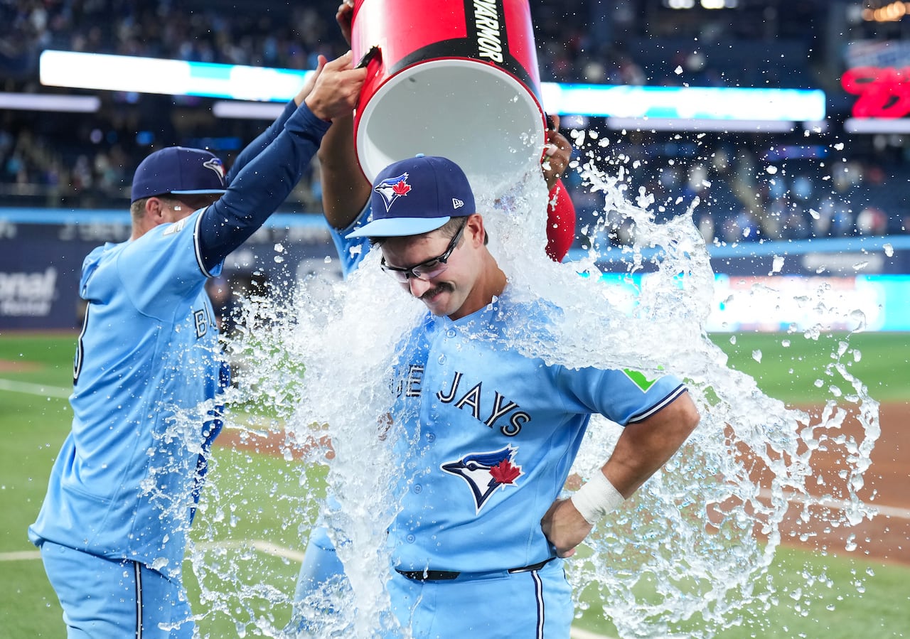 A view of a bucket of ice water being dumped on the Blue Jays' Davis Schneider in the aftermath of a team win