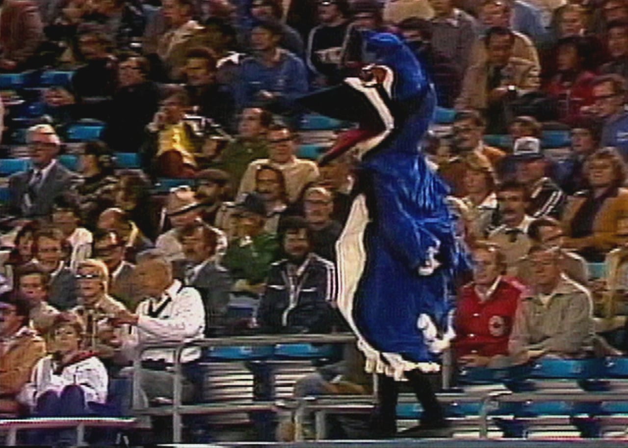Blue and white bird mascot walks among fans at a Blue Jays game