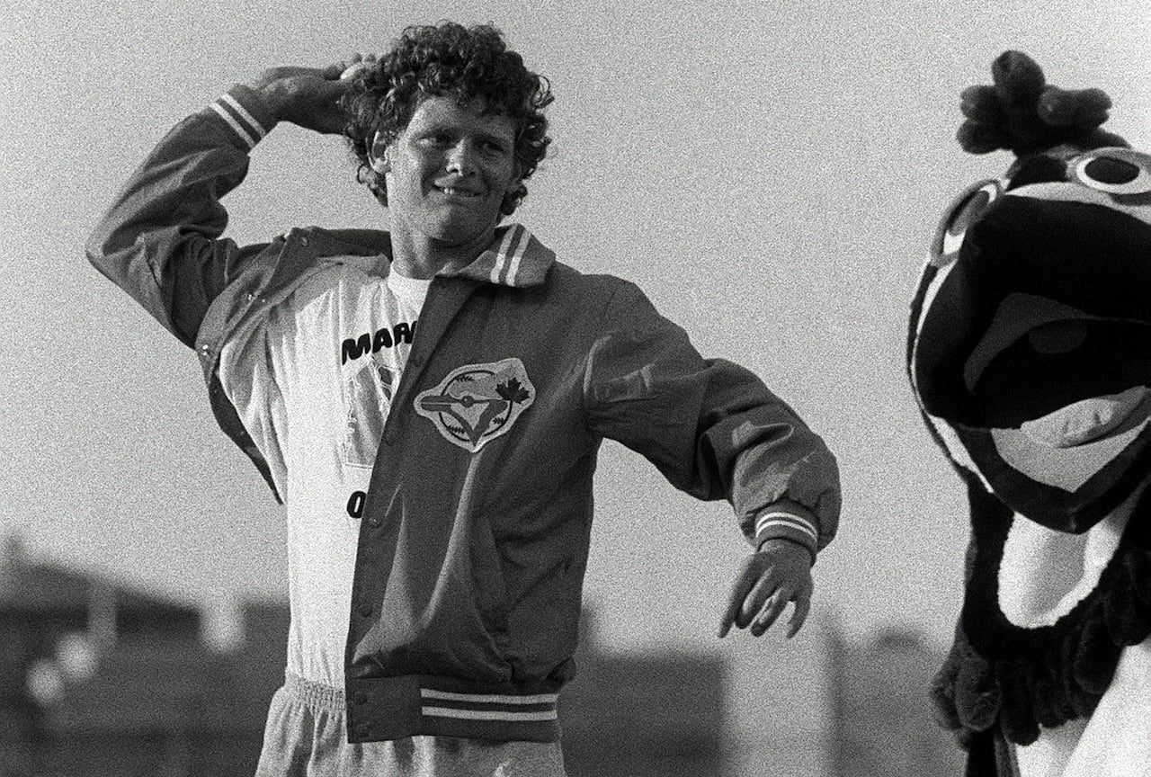 Terry Fox stands on a baseball field holding baseball while BJ Birdy looks on