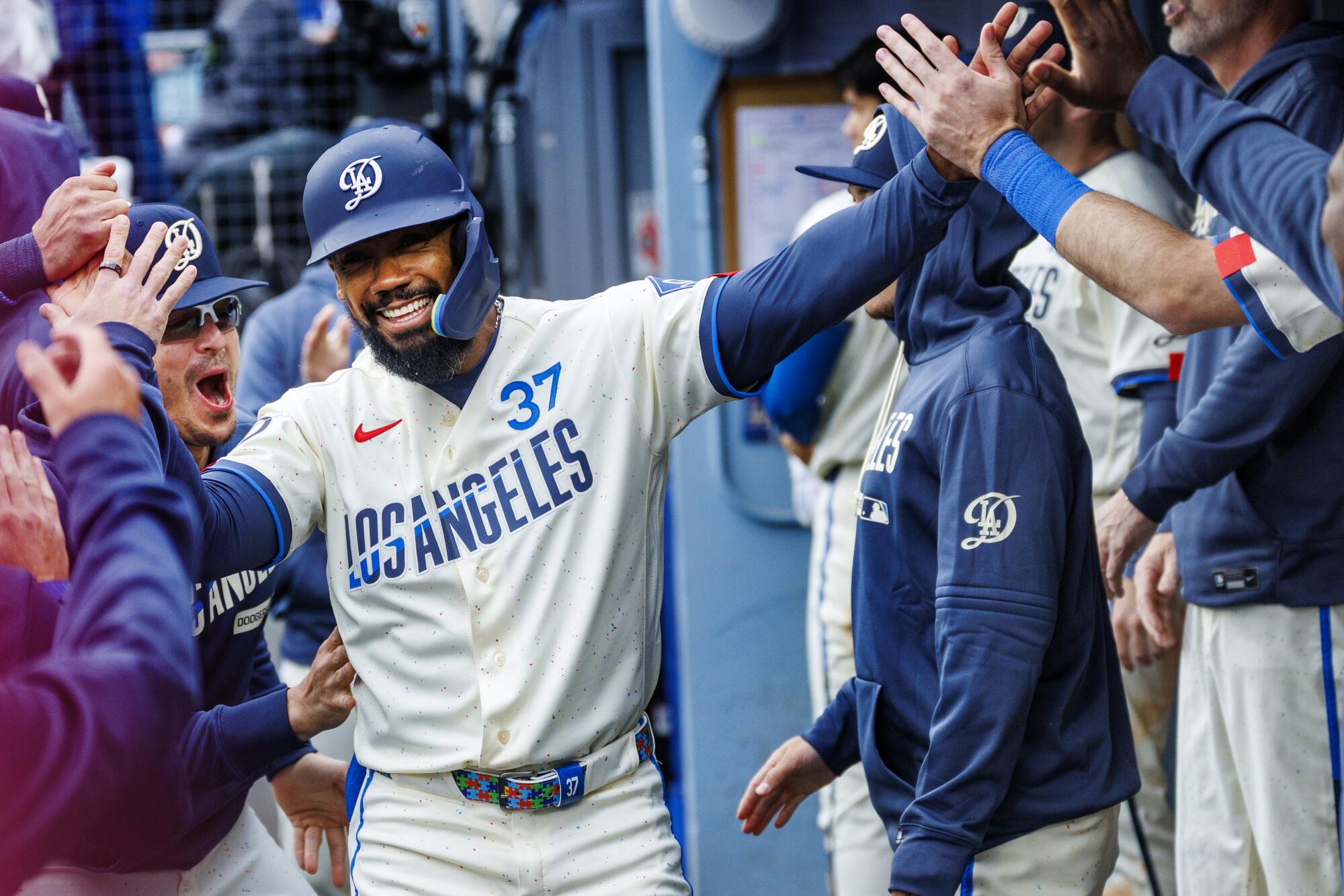 Teoscar Hernández celebrates with teammates in the dugout after scoring on a two-run single by Dalton Rushing.