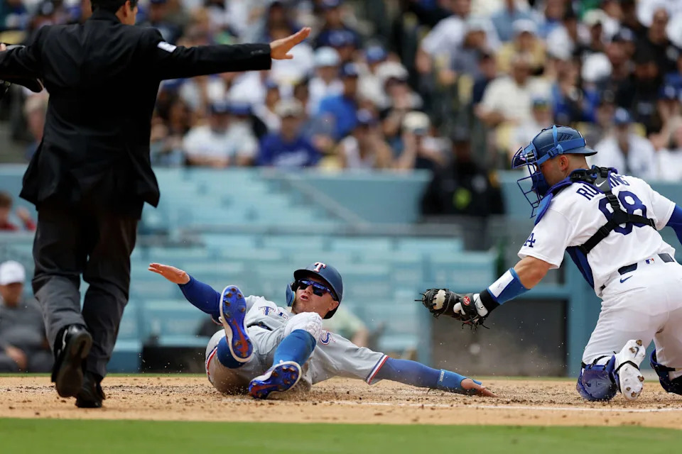 Texas Rangers' Joc Pederson (3) slides into home plate as Los Angeles Dodgers catcher Dalton Rushing (68) goes to tag him with the ball during the third inning of a baseball game Sunday, April 12, 2026, in Los Angeles. (AP Photo/Caroline Brehman) (Caroline Brehman/AP)