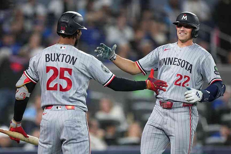Minnesota Twins' Brooks Lee (22) celebrates his hits a solo home run with Byron Buxton during the third inning of a baseball action against the Toronto Blue Jays in Toronto, Saturday, April 11, 2026. (Nathan Denette/The Canadian Press via AP)