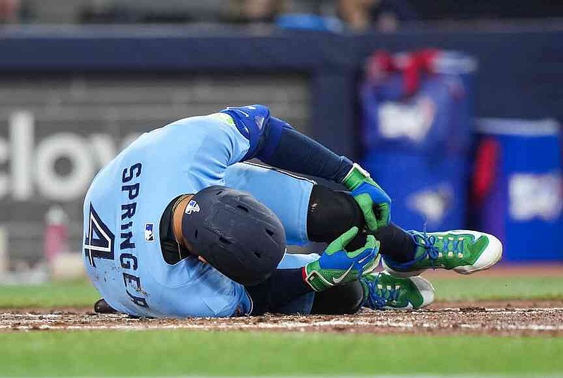 Toronto Blue Jays designated hitter George Springer falls to the ground after taking a foul ball off his foot while playing against the Minnesota Twins during third-inning baseball game action in Toronto, Saturday, April 11, 2026. (Nathan Denette/The Canadian Press via AP)