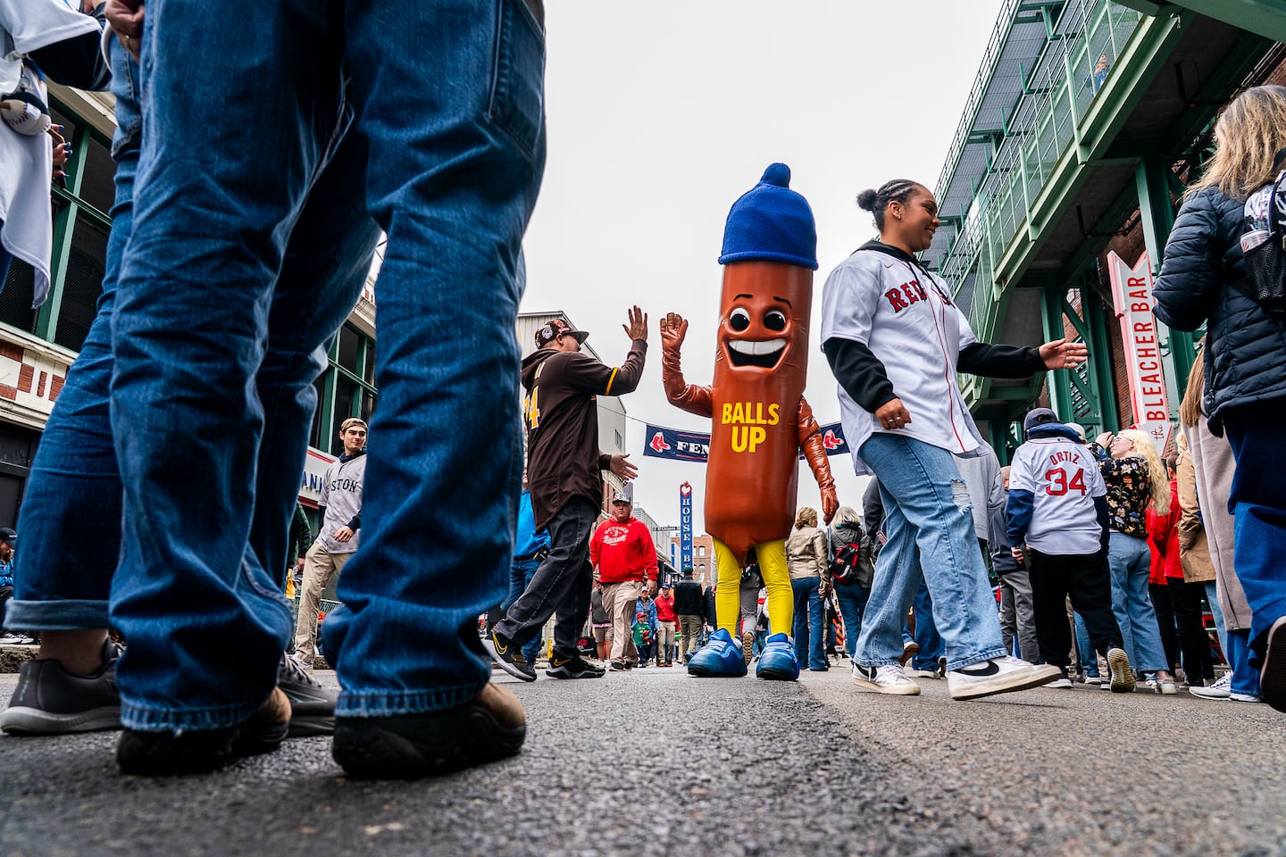 A large sausage shaped character promoting the movie "Balls Up" takes photos with fans outside of Fenway Park.