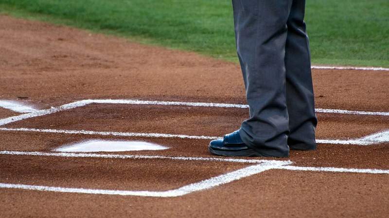 A baseball umpire stands at home plate on a freshly lined field. Photo: Mark Duffel / Unsplash