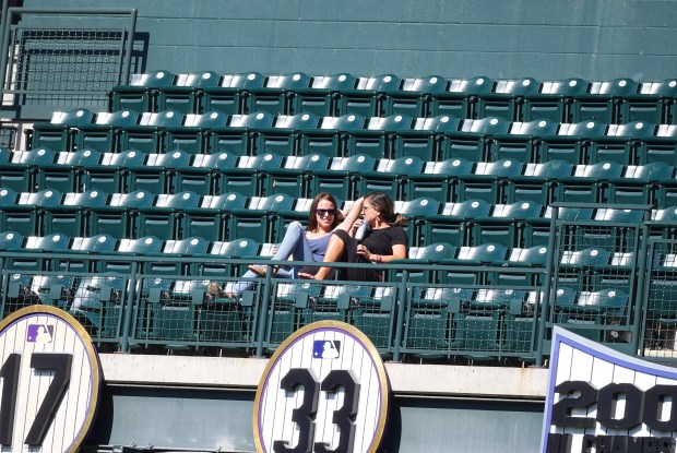 A pair of fans sit in a section of Coors Field in the seventh inning of a baseball game between the Colorado Rockies and the Miami Marlins Thursday, Sept. 18, 2025, in Denver. (AP Photo/David Zalubowski)