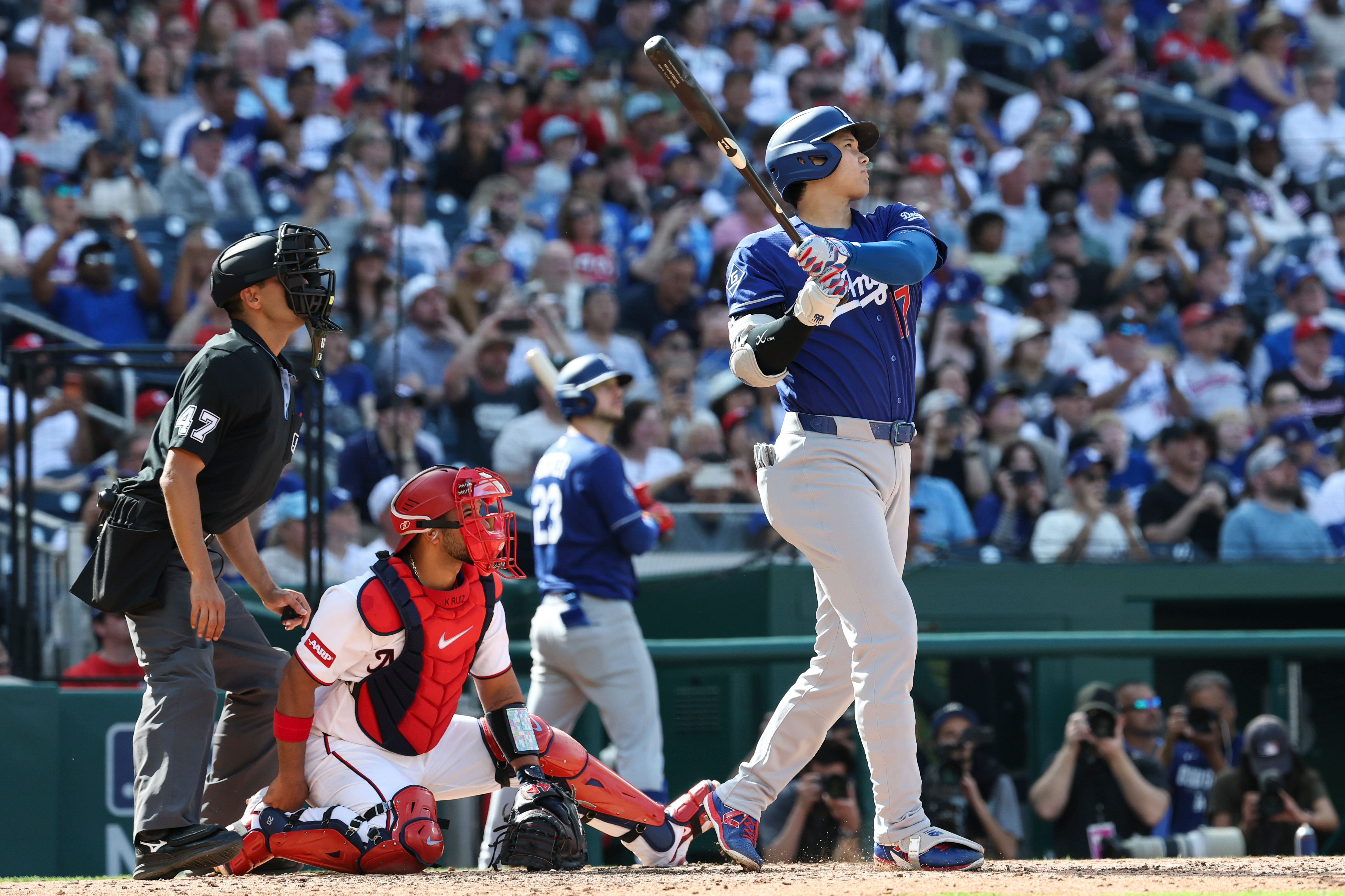 Dodgers star Shohei Ohtani, right, follows through on his swing...