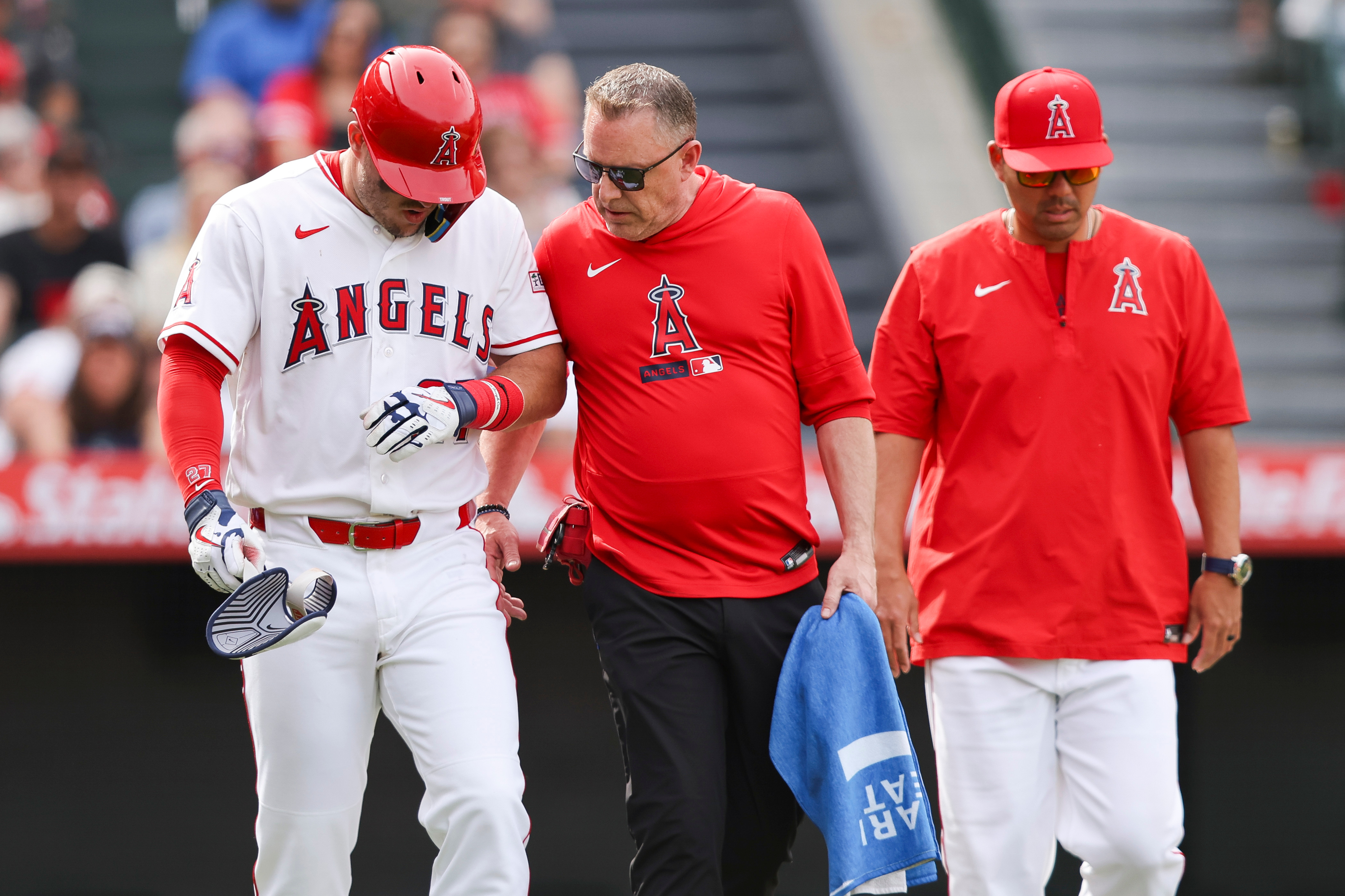 Angels’ Mike Trout, left, looks down as trainer Mike Frostad,...