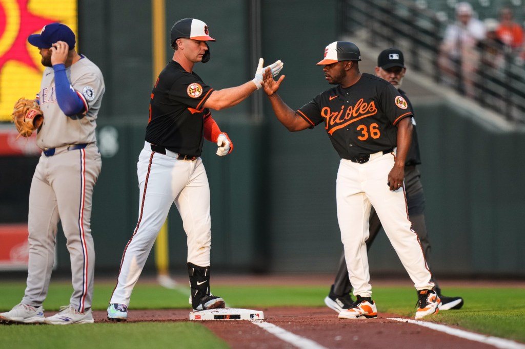 Baltimore Orioles' Pete Alonso, center, celebrates with first base coach Jason Bourgeois (36) after hitting a single during the first inning of a baseball game against the Texas Rangers, Tuesday, March 31, 2026, in Baltimore. 
