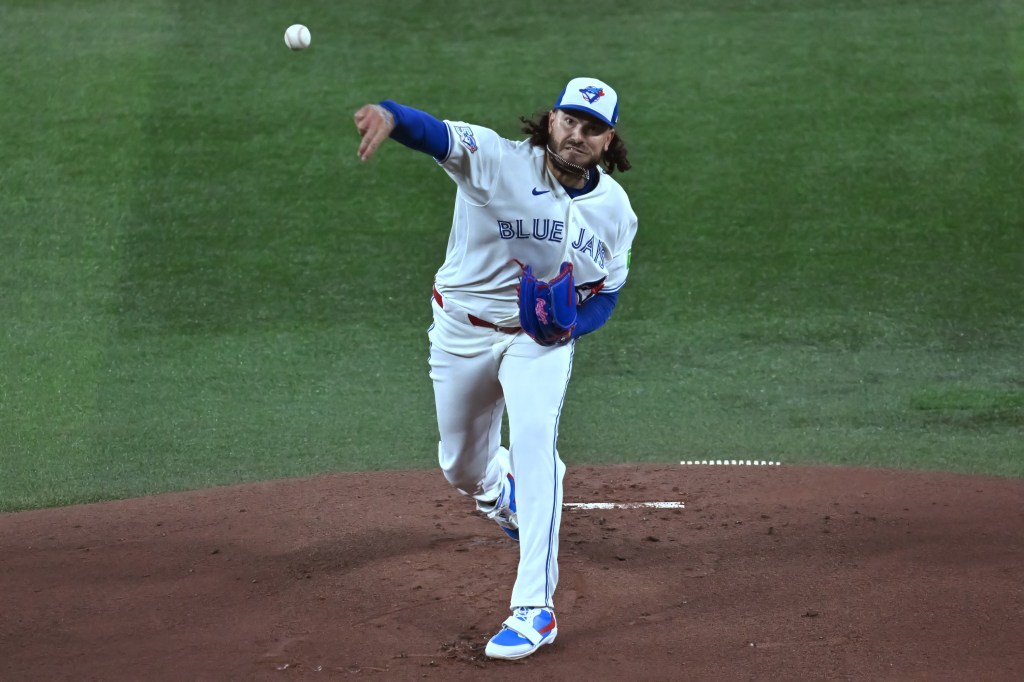 A Blue Jays pitcher on the mound, throwing a baseball.