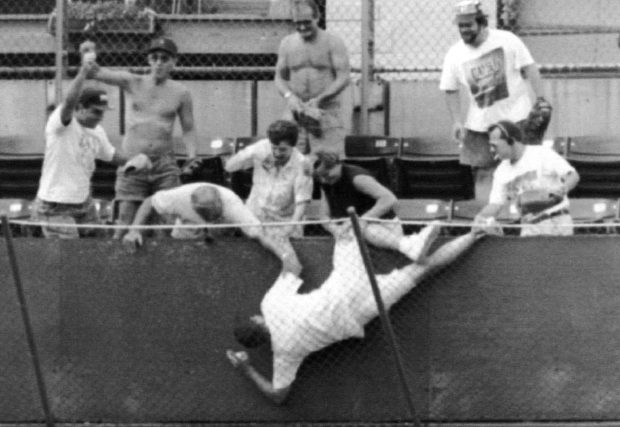A fan falls into the left-field basket after trying to grab Andre Dawson's home run ball during a Cubs game on Sept. 17, 1982, at Wrigley Field. (Chicago Tribune historical photo)