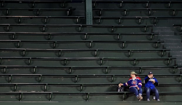 Two Chicago Cubs fans sit in the upper center field bleachers without any other fans around in the second inning of a game between the Cubs and the Los Angeles Angels at Wrigley Field in Chicago on March 31, 2026. (Chris Sweda/Chicago Tribune)