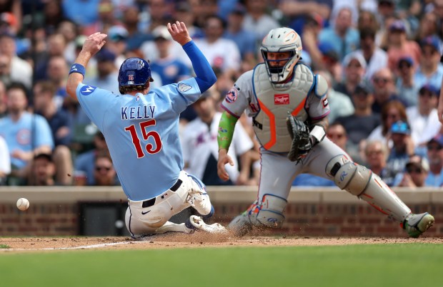 New York Mets catcher Francisco Alvarez receives a late throw as Chicago Cubs catcher Carson Kelly (15) slides in safely at home to score on a sacrifice fly by teammate Dansby Swanson in the seventh inning of a game at Wrigley Field in Chicago on April 17, 2026. (Chris Sweda/Chicago Tribune)