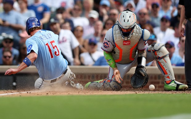 New York Mets catcher Francisco Alvarez receives a late throw as Chicago Cubs catcher Carson Kelly (15) slides in safely at home to score on a sacrifice fly by teammate Dansby Swanson in the seventh inning of a game at Wrigley Field in Chicago on April 17, 2026. (Chris Sweda/Chicago Tribune)