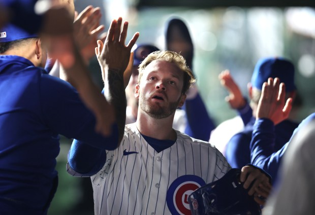 Chicago Cubs left fielder Ian Happ (8) is congratulated by his teammates in the dugout after scoring on a two-run single by Michael Busch in the sixth inning of a game against the Philadelphia Phillies at Wrigley Field in Chicago on April 21, 2026. (Chris Sweda/Chicago Tribune)