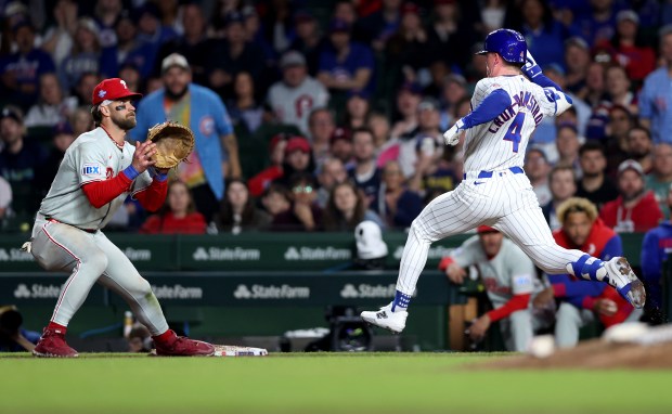 Chicago Cubs center fielder Pete Crow-Armstrong (4) beats out a throw to Philadelphia Phillies first baseman Bryce Harper on a bunt single for Crow-Armstrong in the eighth inning of a game at Wrigley Field in Chicago on April 21, 2026. (Chris Sweda/Chicago Tribune)