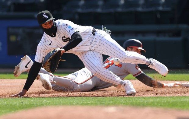 Chicago White Sox first baseman Lenyn Sosa is unable to make a catch as Baltimore Orioles shortstop Blaze Alexander slides back safely to first base in the fourth inning of a game at Rate Field in Chicago on April 7, 2026. After the ball got away, Alexander advanced to second base on the pickoff error by White Sox catcher Edgar Quero. (Chris Sweda/Chicago Tribune)