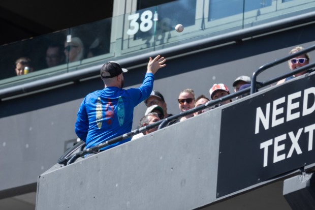 A fan tosses a foul ball to another fan during the second inning of a game against the Toronto Blue Jays at Rate Field on Sunday, April 5, 2026. (Josh Boland/Chicago Tribune)