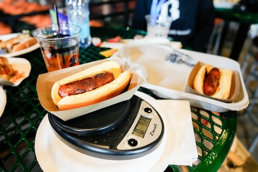 Baltimore Banner reporter Allan James Vestal measures the weight of hot dogs inside Oriole Park at Camden Yards in Baltimore, Md., on Monday, March 30, 2026.