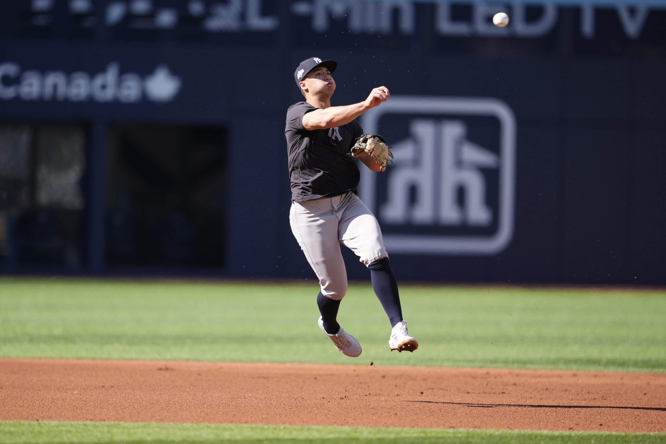 Anthony Volpe throws a ball to first base.