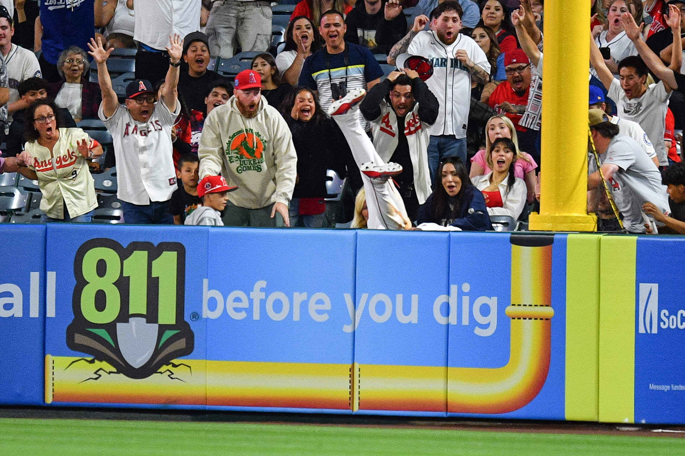 Kayleigh Kraus, seated to the left of a yellow foul pole, reacts as Jo Adell falls head-first into the stands after robbing a home run.