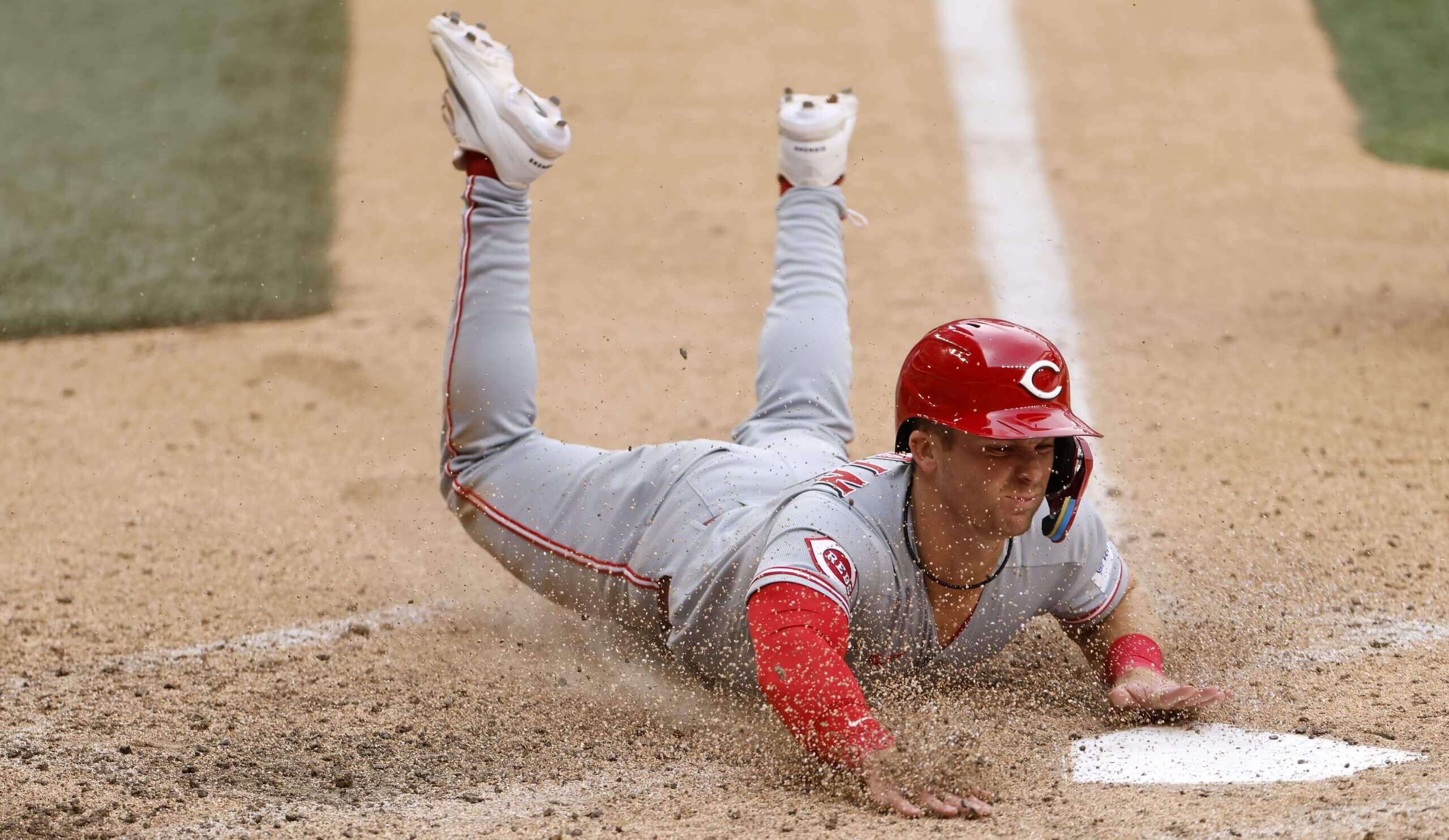 Matt McLain slides headfirst into home plate to score a run.