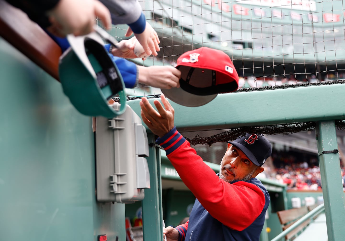 Red Sox manager Alex Cora signs autographs for young fans before the game.
