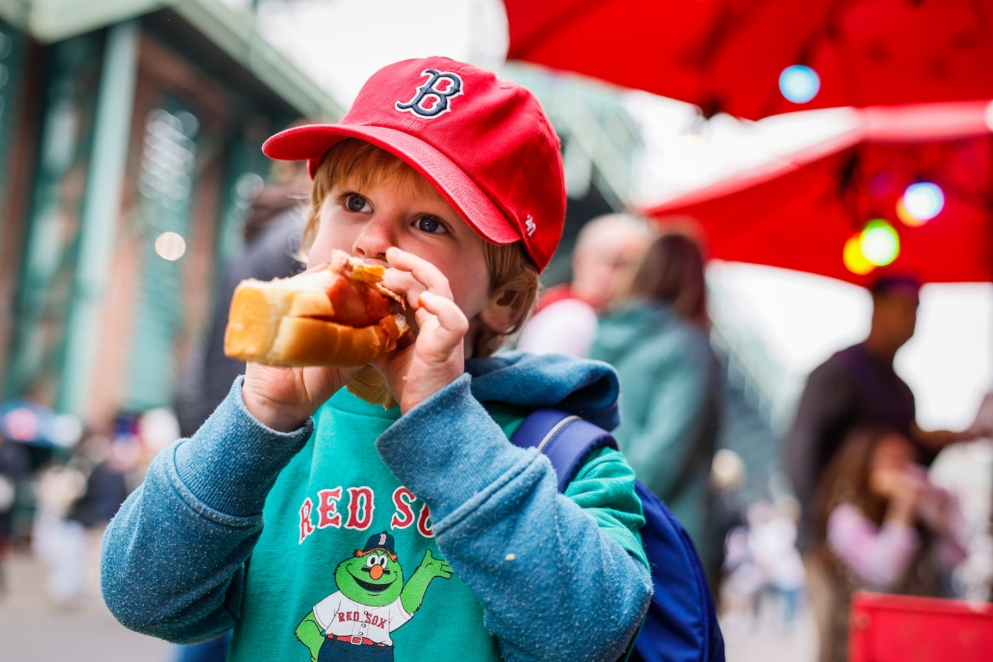 Mark Notaro, 3, eats a hot dog along Lansdowne Street.