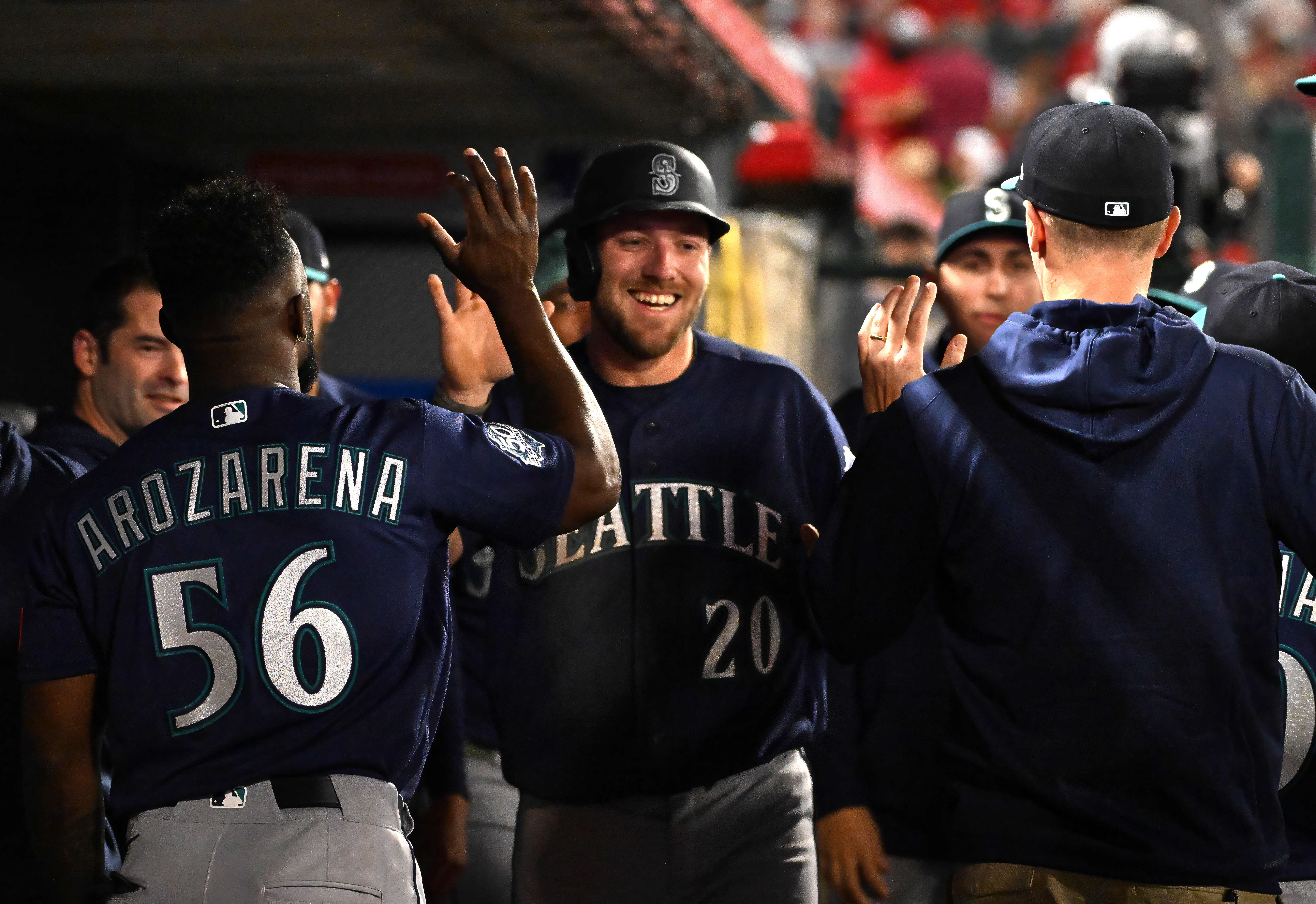 Luke Raley #20 of the Seattle Mariners high fives teammates...