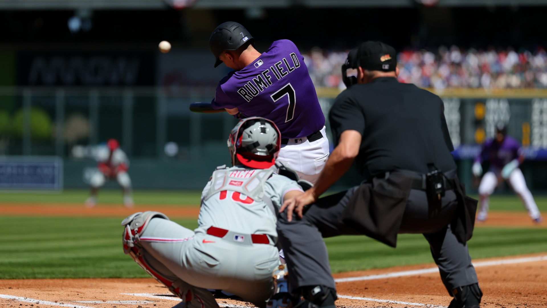 TJ Rumfield #7 of the Colorado Rockies hits a two run home run in the first inning in front of catcher Rafael Marchan #13 of the Philadelphia Phillies and umpire Andy Fletcher #49 at Coors Field on April 5, 2026 in Denver, Colorado. (Photo by Justin Edmonds/Getty Images)