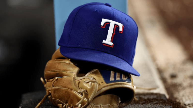 A detailed view of a Texas Rangers logo hat on top of a glove in the dugout against the Los Angeles Dodgers at Dodger Stadium on April 11, 2026 in Los Angeles, California. (Photo by Luke Hales/Getty Images)